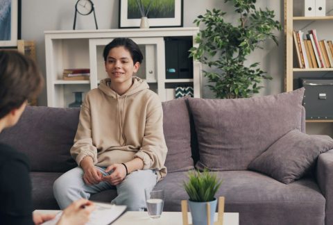 a woman sitting on a couch talking to another woman
