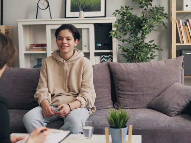 a woman sitting on a couch talking to another woman